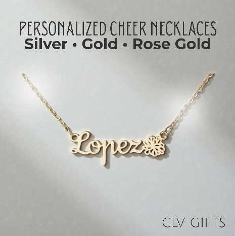 Gold-tone Lopez name necklace with a pom-pom motif on a pale neutral background.